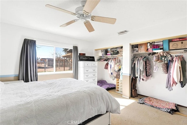 carpeted bedroom featuring multiple closets and ceiling fan