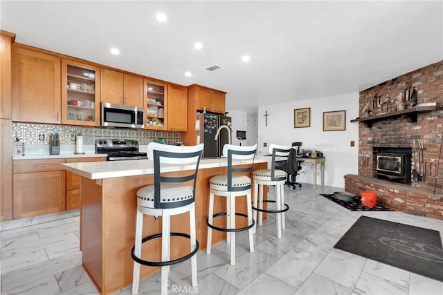 kitchen featuring tasteful backsplash, stainless steel appliances, an island with sink, and a kitchen bar