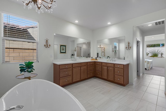 bathroom featuring vanity, a tub, a wealth of natural light, and a notable chandelier