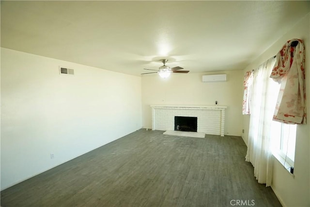 unfurnished living room featuring ceiling fan, a fireplace, dark hardwood / wood-style floors, and a wall mounted AC