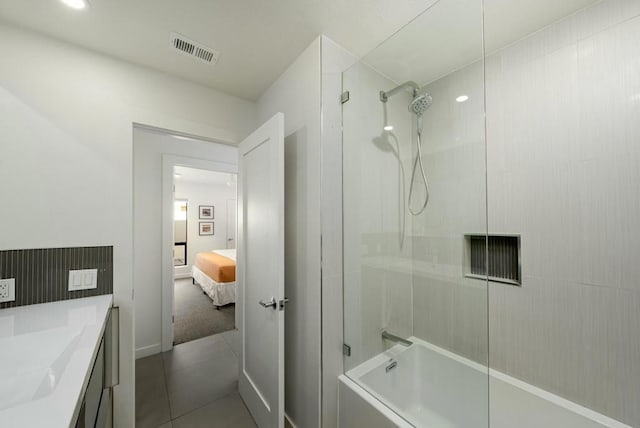 bathroom with tiled shower / bath combo, vanity, and tile patterned flooring