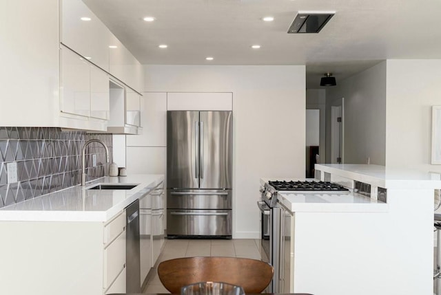 kitchen featuring sink, light tile patterned floors, backsplash, stainless steel appliances, and white cabinets