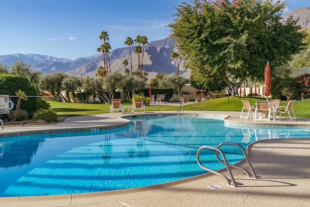 view of pool featuring a mountain view, a patio area, and a lawn