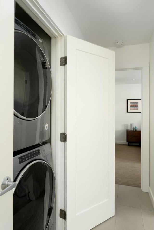 washroom featuring stacked washer and dryer and light tile patterned floors