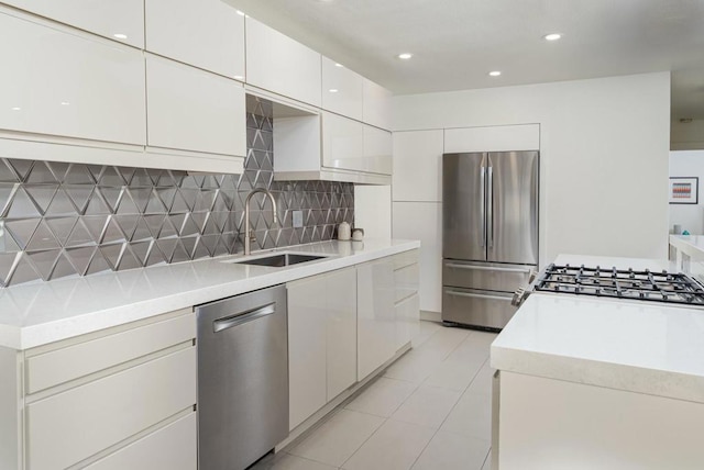 kitchen featuring sink, light tile patterned floors, white cabinets, stainless steel appliances, and backsplash