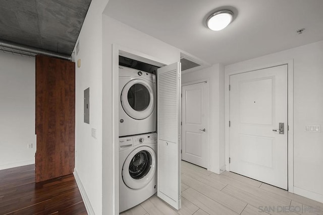 clothes washing area featuring stacked washer / drying machine and light hardwood / wood-style floors