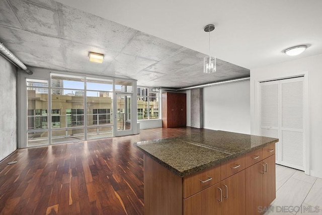 kitchen featuring dark stone countertops, hanging light fixtures, a wealth of natural light, and light hardwood / wood-style floors