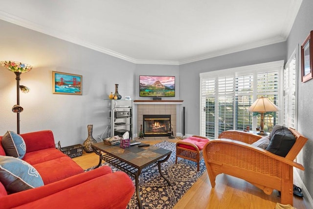 living room with hardwood / wood-style flooring, crown molding, and a tile fireplace