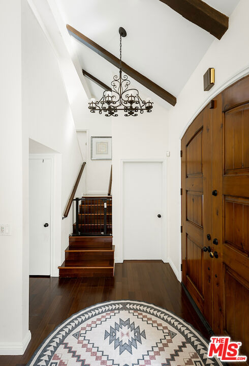 entryway featuring beamed ceiling, high vaulted ceiling, dark hardwood / wood-style floors, and a chandelier