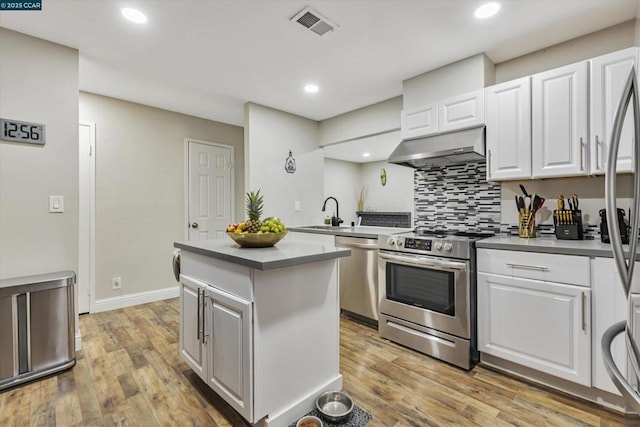 kitchen with stainless steel appliances, light hardwood / wood-style floors, a kitchen island, and white cabinets