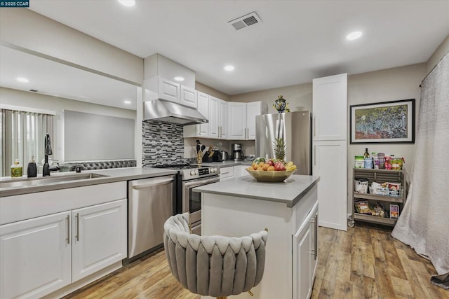 kitchen with white cabinetry, a center island, exhaust hood, stainless steel appliances, and light wood-type flooring