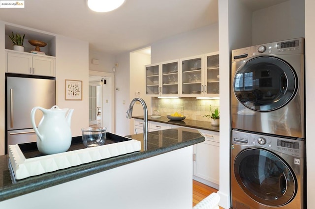 washroom featuring sink, stacked washing maching and dryer, and light hardwood / wood-style floors