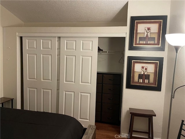 bedroom featuring dark hardwood / wood-style flooring, a closet, and a textured ceiling