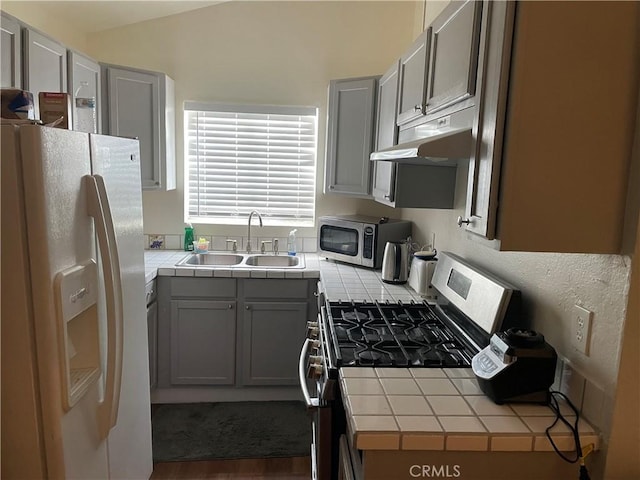 kitchen featuring stainless steel appliances, tile counters, gray cabinets, and sink