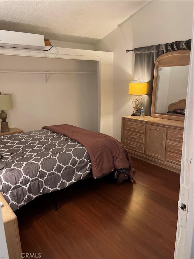 bedroom with dark wood-type flooring, a wall mounted AC, and vaulted ceiling