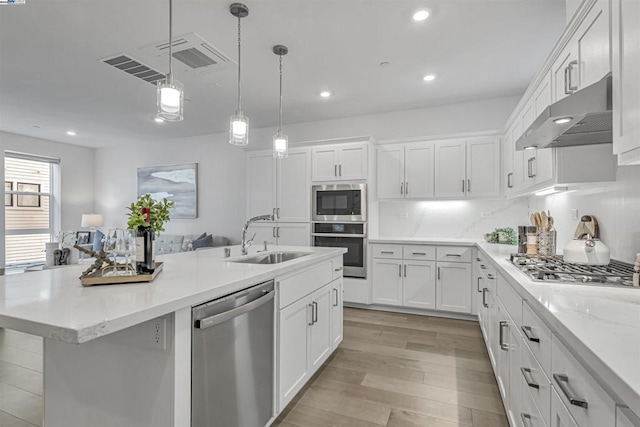 kitchen featuring sink, hanging light fixtures, light wood-type flooring, stainless steel appliances, and white cabinets