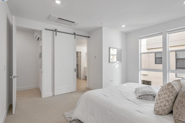 bedroom with light carpet, an AC wall unit, and a barn door