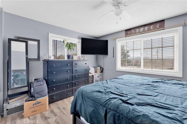 bedroom with hardwood / wood-style floors, a textured ceiling, and ceiling fan