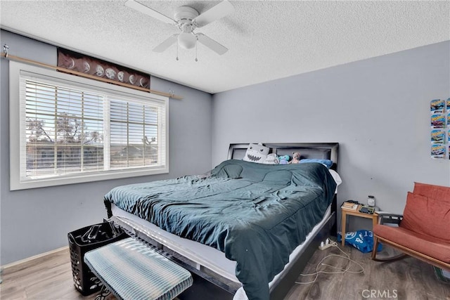 bedroom with ceiling fan, hardwood / wood-style floors, and a textured ceiling