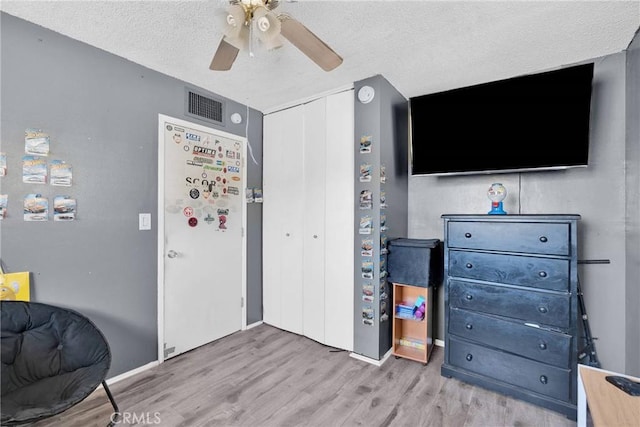 interior space featuring ceiling fan, a textured ceiling, and light hardwood / wood-style floors