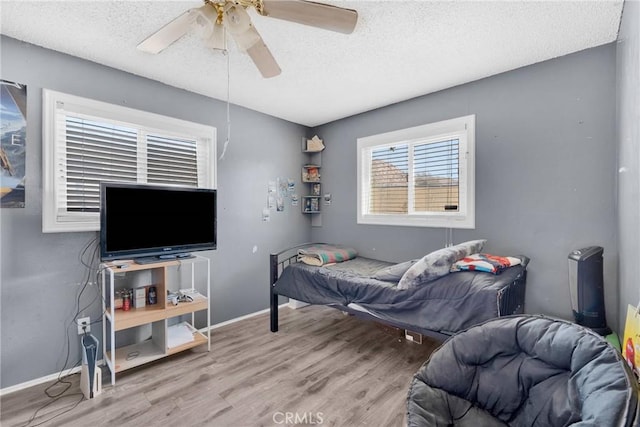 bedroom with hardwood / wood-style flooring, ceiling fan, and a textured ceiling