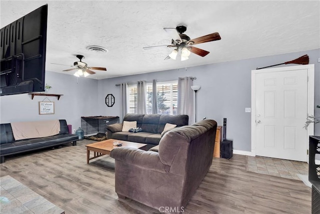 living room with ceiling fan, hardwood / wood-style flooring, and a textured ceiling