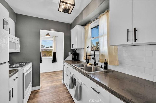 kitchen featuring sink, white cabinetry, dark hardwood / wood-style flooring, white appliances, and decorative backsplash