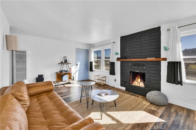 living room with a brick fireplace and hardwood / wood-style floors