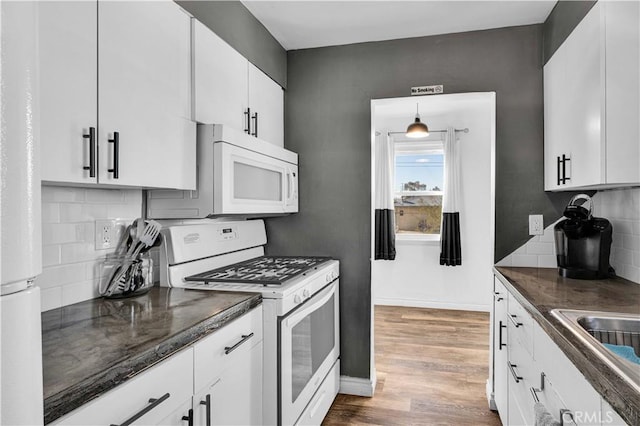 kitchen with pendant lighting, white appliances, hardwood / wood-style flooring, white cabinetry, and backsplash