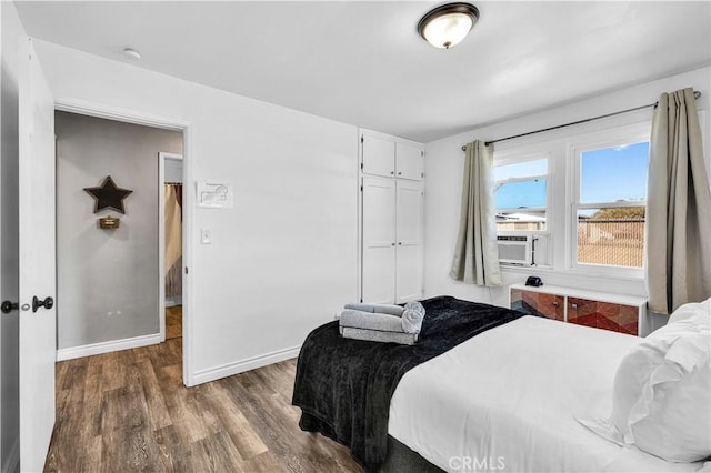 bedroom with dark hardwood / wood-style flooring, cooling unit, and a closet