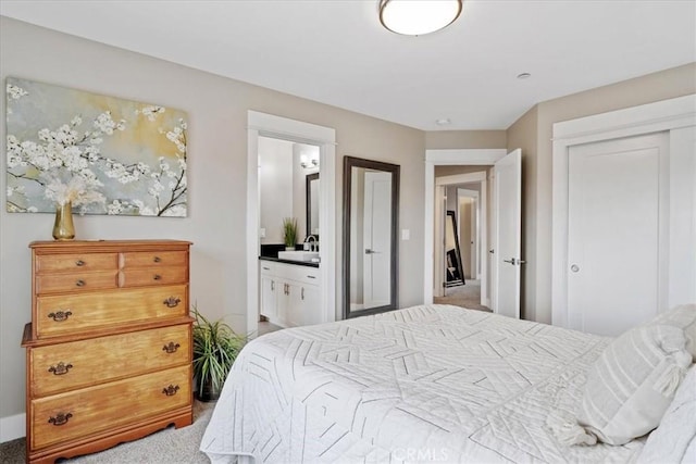 bedroom featuring carpet, sink, ensuite bath, and a closet