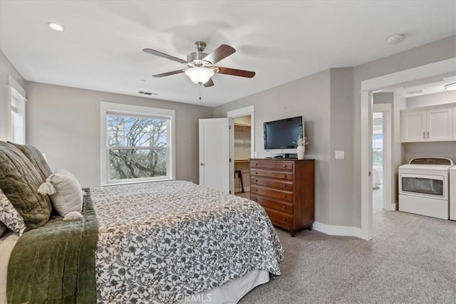 bedroom featuring ceiling fan, light colored carpet, washer / clothes dryer, and a walk in closet