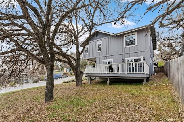 rear view of property featuring a wooden deck and a lawn