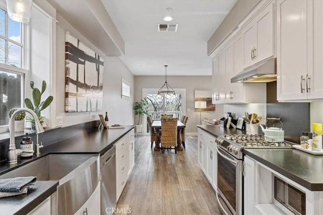 kitchen featuring decorative light fixtures, white cabinetry, sink, stainless steel appliances, and light wood-type flooring