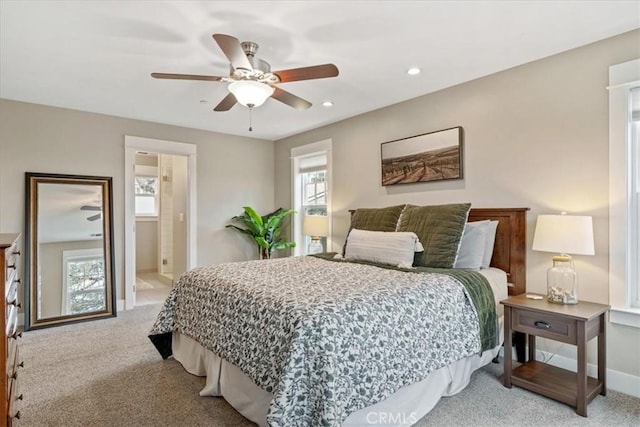 carpeted bedroom with multiple windows, ensuite bath, and ceiling fan