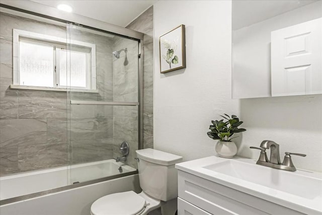 full bathroom featuring vanity, bath / shower combo with glass door, and toilet