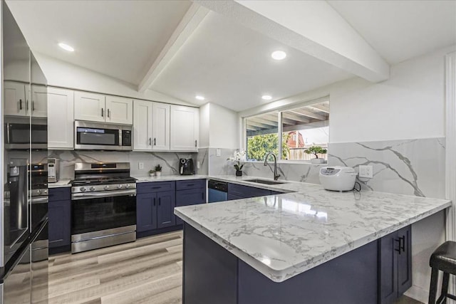 kitchen with sink, kitchen peninsula, white cabinets, and appliances with stainless steel finishes