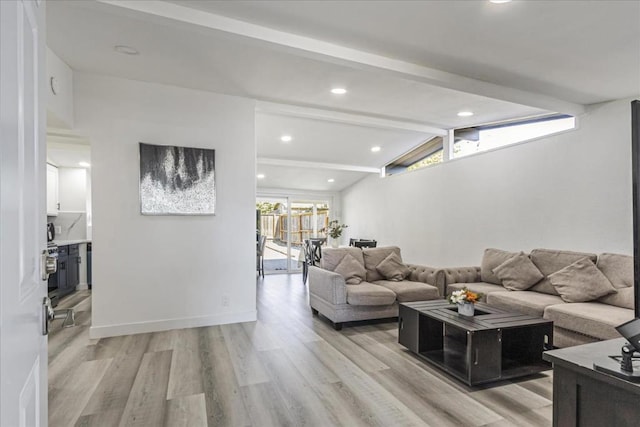 living room featuring lofted ceiling with beams and light hardwood / wood-style flooring