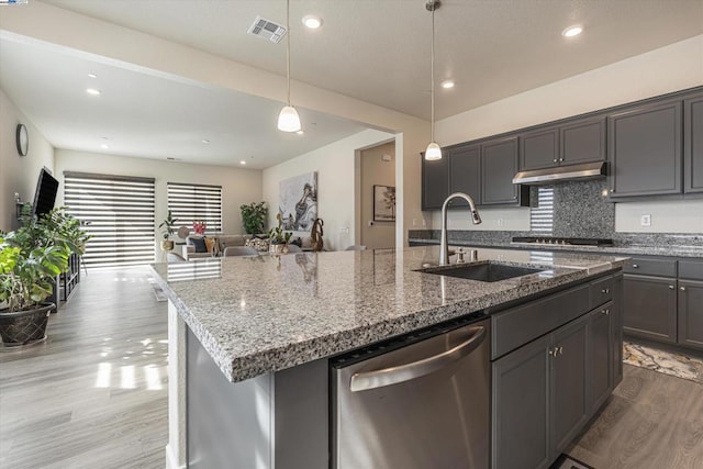 kitchen with sink, a kitchen island with sink, stone countertops, decorative light fixtures, and stainless steel dishwasher