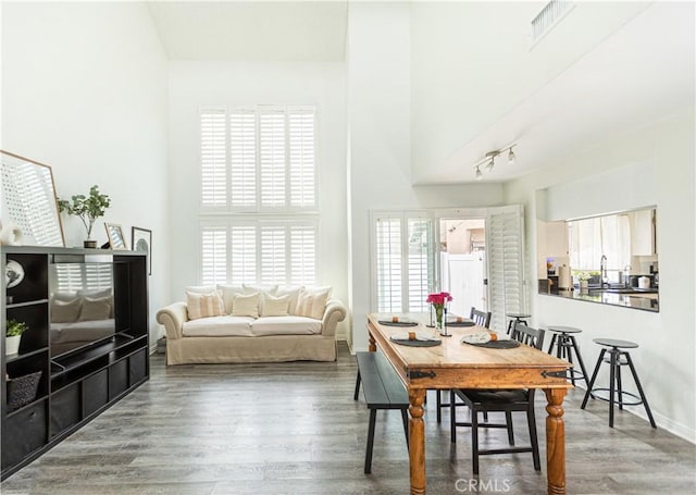 dining space with dark wood-type flooring and a towering ceiling