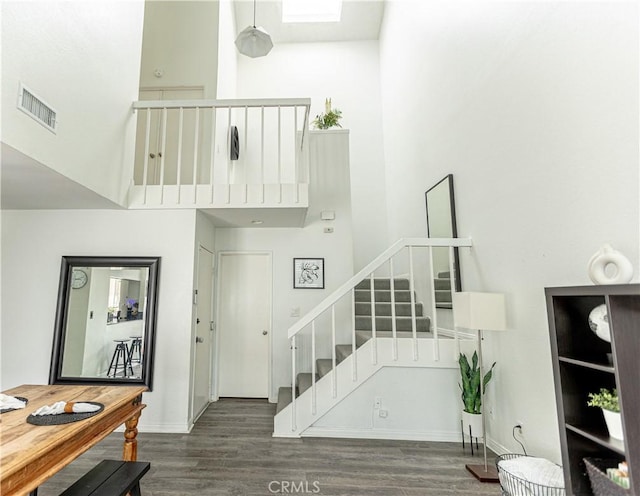 stairs with wood-type flooring and a high ceiling