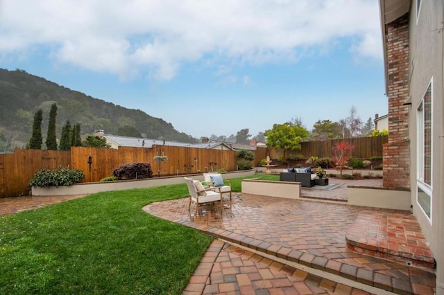 view of yard with an outdoor living space, a mountain view, and a patio area