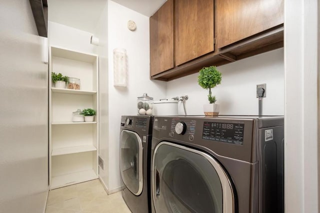 washroom with cabinets, independent washer and dryer, and light tile patterned flooring