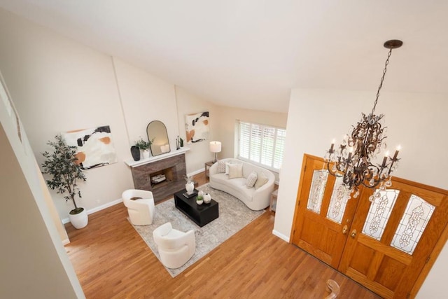 living room featuring lofted ceiling, wood-type flooring, a fireplace, and a chandelier