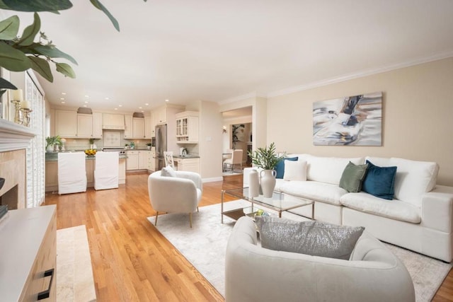 living room featuring a premium fireplace, ornamental molding, and light hardwood / wood-style flooring