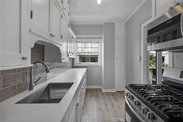 kitchen featuring sink, decorative backsplash, stainless steel appliances, and white cabinets