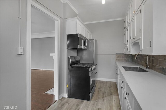 kitchen featuring sink, ornamental molding, appliances with stainless steel finishes, white cabinets, and backsplash