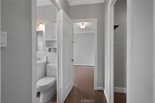 bathroom with hardwood / wood-style flooring, crown molding, and toilet