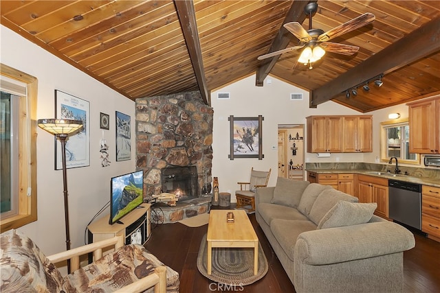 living room featuring sink, a stone fireplace, dark wood-type flooring, and lofted ceiling with beams