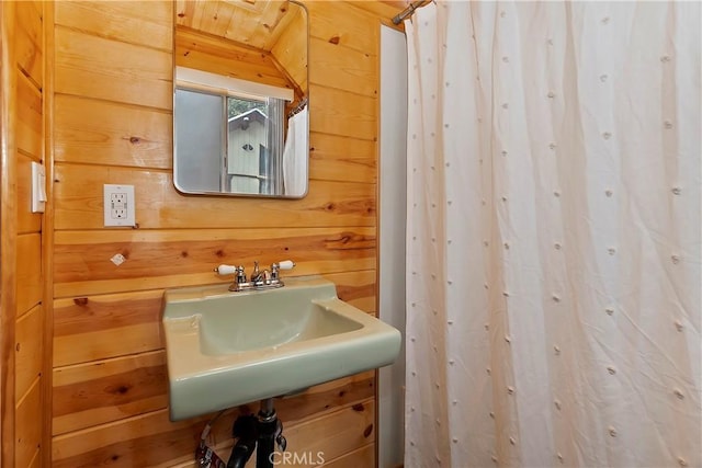 bathroom featuring wooden walls and sink